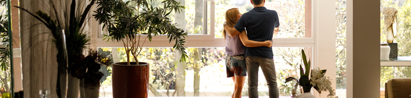 Mature couple looking out the living room window.