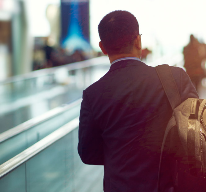 Business man walking through an airport with backpack.